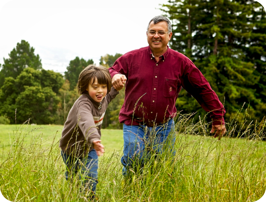 Father and child running through tall grass and smiling